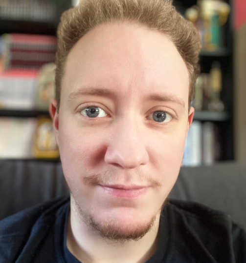 Autor Nick Böcker: Rot-blonde Haare, blaue Augen, ein leichter Barten und ein schmales Lächeln auf den Lippen
